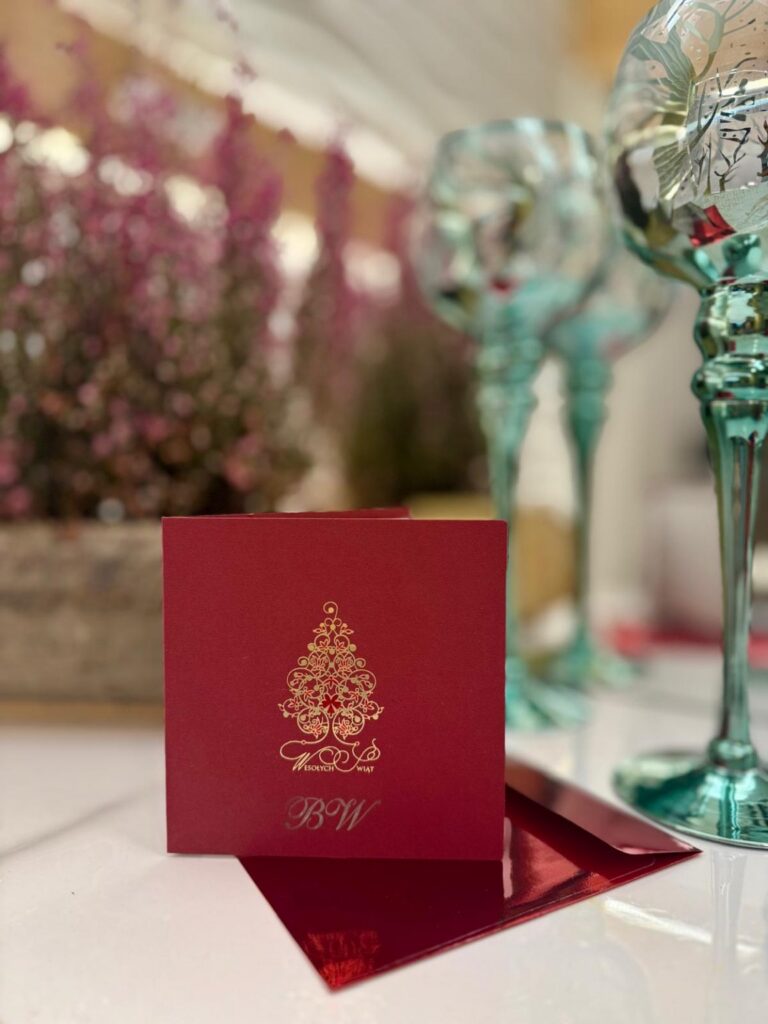 Świąteczny voucher upominkowy w czerwonej kopercie ze złotą choinką